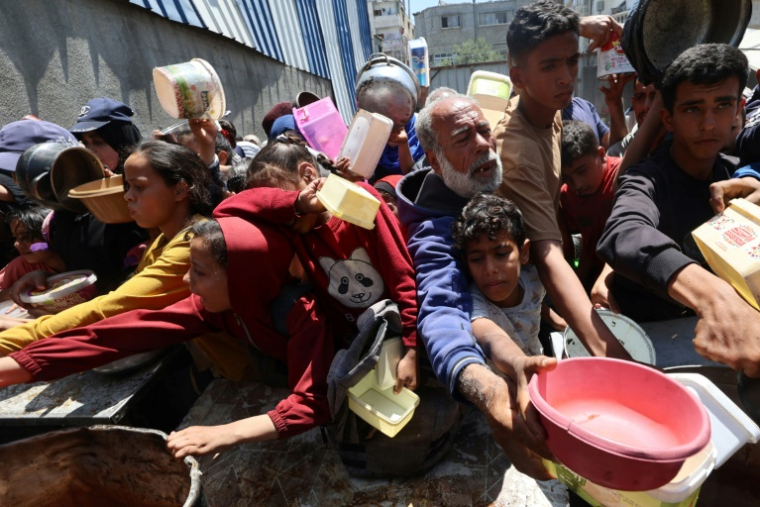 Des Palestiniens attendent de recevoir un repas chaud dans une cuisine caritative de Nousseirat dans le centre de la bande de Gaza, le 4 mai 2025 ( AFP / Eyad BABA )