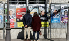 Des passants regardent les affiches électorales des candidats aux municipales à Paris le 9 mars 2026 ( AFP / Ludovic MARIN )