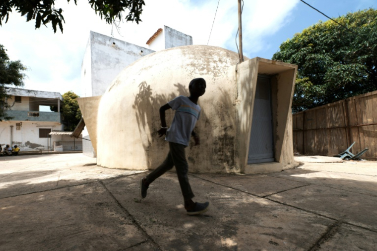 A garçon passe, le 27 août à Ouakam, banlieue de Dakar, devant une maison-bulle, habitations construites dans les années 1950 dans la capitale du Sénégal ( AFP / SEYLLOU )