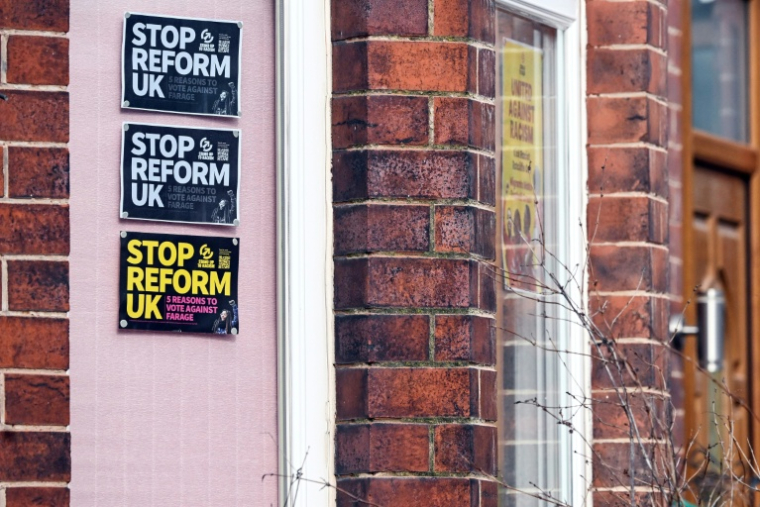 Des affiches en faveur du parti anti-immigration Reform UK sont visibles sur une maison à Denton, dans le Grand Manchester, au nord-ouest de l'Angleterre, le 25 février 2026, à la veille de la cruciale élection législative partielle de Gorton et Denton.  ( AFP / Paul ELLIS )