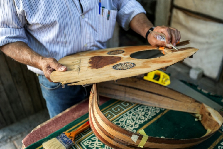 Le luthier palestinien Souhail Abou Chawich dans son atelier de réparation d'ouds, au camp de réfugiés de Nousseirat, dans le centre de la bande de Gaza, le 23 juin 2026 ( AFP / Eyad Baba )