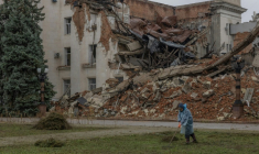 Un employé municipal ramasse de l'herbe coupée près d'un bâtiment administratif en partie détruit par une frappe russe, le 30 octobre 2026 à Kherson, dans le sud de l'Ukraine ( AFP / Roman PILIPEY )