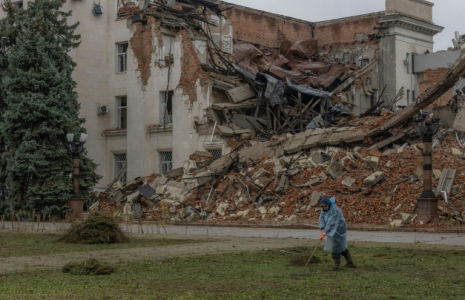 Un employé municipal ramasse de l'herbe coupée près d'un bâtiment administratif en partie détruit par une frappe russe, le 30 octobre 2026 à Kherson, dans le sud de l'Ukraine  ( AFP / Roman PILIPEY )