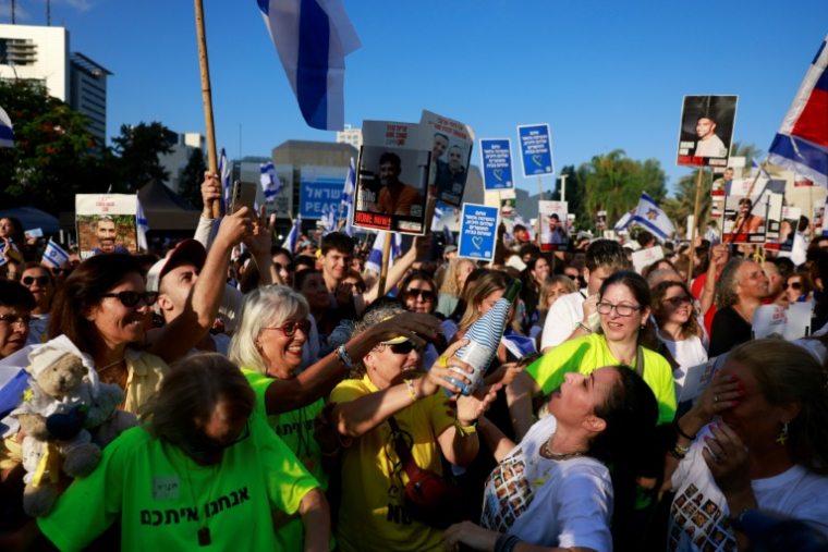 Des personnes font la fête sur la place des Otages à Tel-Aviv après l'annonce de la remise par le Hamas de sept otages retenus à Gaza à la Croix-Rouge, le 13 octobre 2025 ( AFP / Menahem KAHANA )