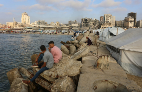 Des Palestiniens se rassemblent sur la plage de Gaza-ville, en bordure de tentes intallées par des déplacés, le 8 juin 2025 ( AFP / Omar AL-QATTAA )