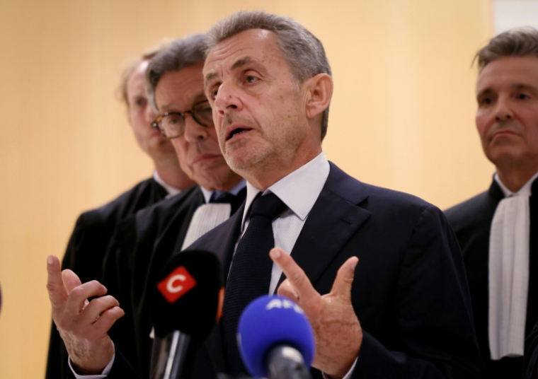 L'ancien président Nicolas Sarkozy (C) s'adresse à la presse aux côtés de son avocat Jean-Michel Darrois (2e g) après le verdict du procès libyen pour financement illégal de sa campagne de 2007, au tribunal de Paris, le 25 septembre 2025 ( AFP / Alain JOCARD )
