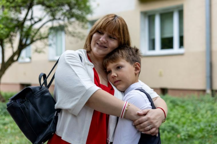 L'opposante bélarusse Antanina Kanavalava serre dans ses bras son fils, Ivan, le jour de la rentrée des classes à Varsovie, le 1er septembre 2025 en Pologne ( AFP / Wojtek RADWANSKI )
