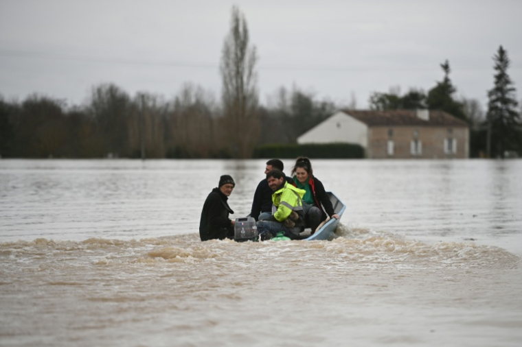 Des habitants s'entraident pour évacuer la zone par bateau alors que la Garonne déborde et inonde un quartier résidentiel de Tonneins, dans le sud-ouest de la France, le 13 février 2026 ( AFP / Christophe ARCHAMBAULT )