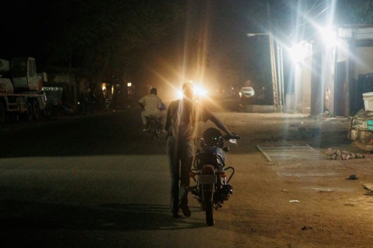 Un homme pousse sa moto qui n'a plus d'essence à Bamako, le 26 octobre 2025. ( AFP / - )