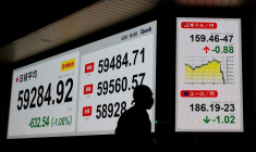 Un piéton passe devant un tableau de cotation indiquant la moyenne de l'action Nikkei et le taux de change USD/JPY à l'extérieur d'une maison de courtage à Tokyo