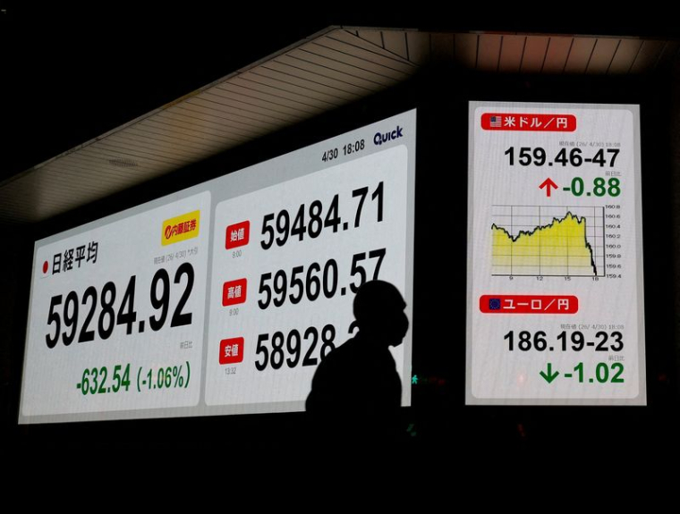 Un piéton passe devant un tableau de cotation indiquant la moyenne de l'action Nikkei et le taux de change USD/JPY à l'extérieur d'une maison de courtage à Tokyo
