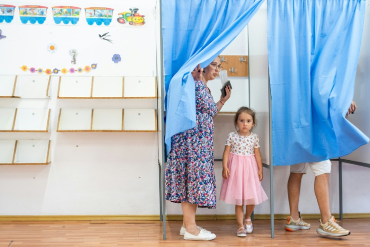 Une femme vote avec sa fille pour la présidentielle roumaine, le 4 mai 2025 à Ciocanesti ( AFP / Mihai Barbu )