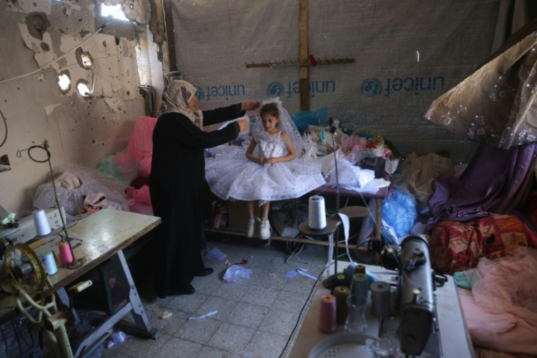 Une petite fille palestinienne essaie une robe de princesse dans une boutique à Khan Younès dans le sud de la bande de Gaza le 13 juin 2026. ( AFP / Bashar Taleb )