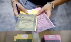 Une personne tient des bulletins de vote dans un bureau de vote