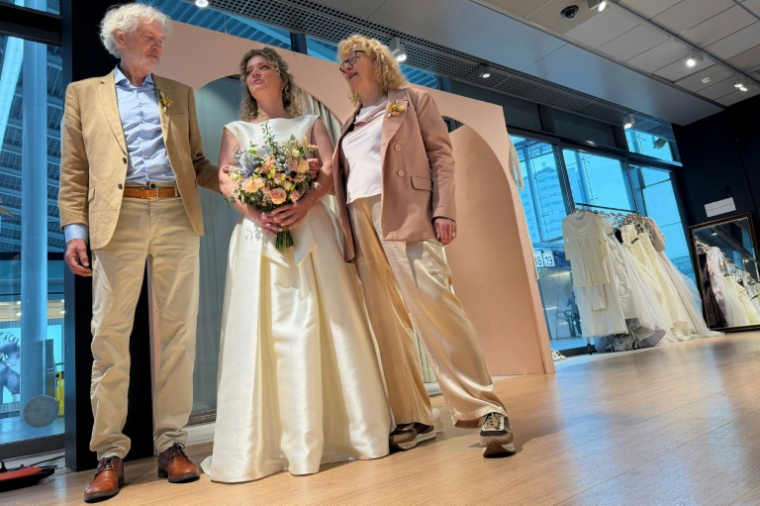 Lara Beters (c), communicante en développement durable, dans une boutique éphémère "Free Fashion" où elle a trouvé sa robe de mariée, à la gare d'Utrecht, le 2 avril 2026 aux Pays-Bas ( AFP / Stéphanie HAMEL )
