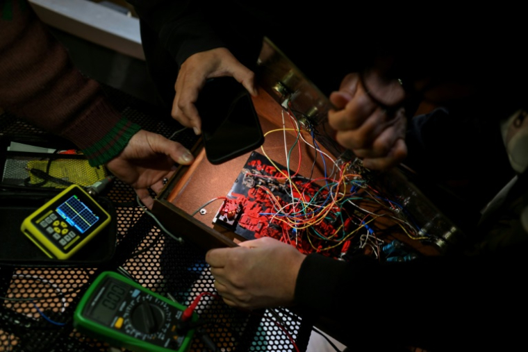 Des personnes réparent un ordinateur hors d'usage lors de la 3e rencontre fédérale de Cyberciruja à Buenos Aires, le 16 août 2025 en Argentine ( AFP / Luis ROBAYO )