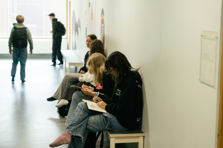 Des élèves assis sur un banc dans un couloir pendant une pause entre les cours au  collège Kungsvägens skola, le 21 août 2025 à Sipoo, en Finlande ( AFP / Alessandro RAMPAZZO )