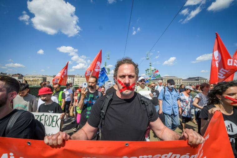 Des manifestants marchent en silence, scotch sur la bouche, pour protester contre un projet de loi ciblant les ONG et les médias financés depuis l'étranger, le 1er juin 2025 à Budapest ( AFP / Ferenc ISZA )