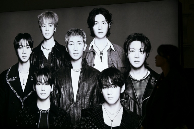 Un visiteur passe devant une photo du groupe de K-pop BTS dans un grand magasin de Séoul, le 20 mars 2026 ( AFP / Jung Yeon-je )