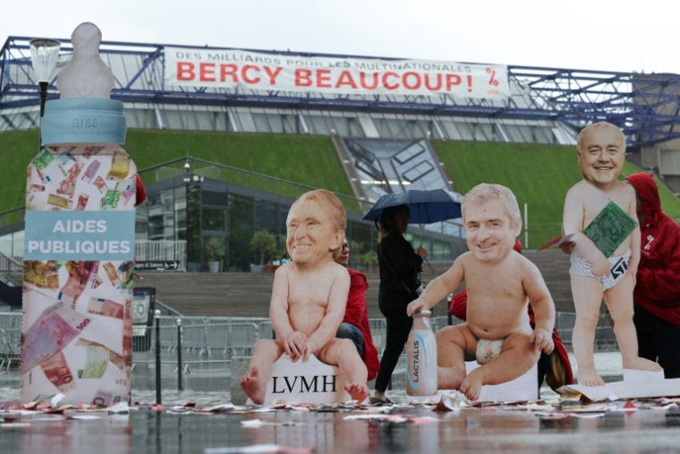 Des silhouettes de bébé arborant le visage des patrons de LVMH, Bernard Arnault, de Lactalis, Emmanuel Besnier, et de ST Microelectronics, Jean-Marc Chery, installés par des militants d'Attac France devant l'Accor Arena, près du ministère de l'Economie, à Paris, pour protester contre les subventions aux multinationales, le mardi 2 juin 2026  ( AFP / Kenzo TRIBOUILLARD )