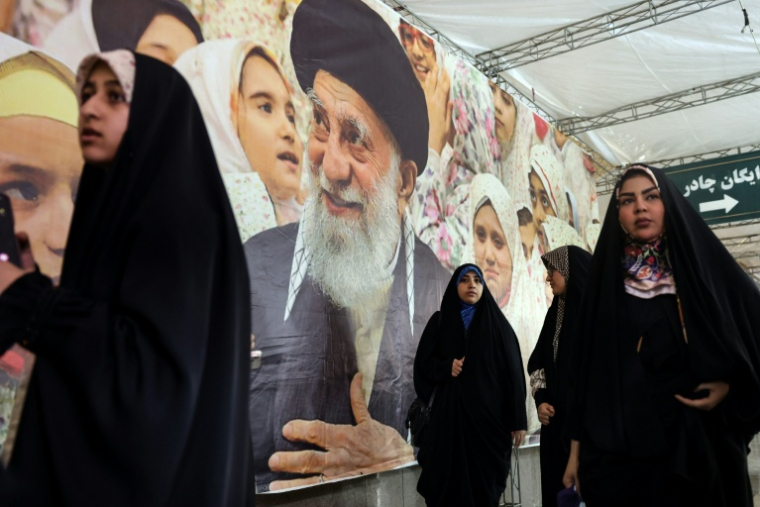 Des Iraniennes longent un portrait du guide suprême, l'ayatollah Ali Khamenei, à la grande mosquée de l'imam Khomeini de Téhéran, le 22 février 2026 ( AFP / STRINGER )