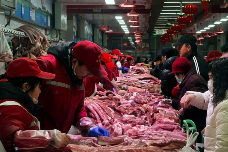 Des vendeurs de porc s'occupent des clients dans un marché à Pékin
