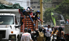 Des bénévoles distribuant de la nourriture et de l'eau à des motocyclistes participant au transport d'aide humanitaire à Caraballeda, dans l'État de La Guaira (Venezuela), le 27 juin 2026, à la suite de séismes ( AFP / Federico PARRA )