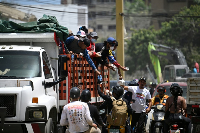 Des bénévoles distribuant de la nourriture et de l'eau à des motocyclistes participant au transport d'aide humanitaire à Caraballeda, dans l'État de La Guaira (Venezuela), le 27 juin 2026, à la suite de séismes ( AFP / Federico PARRA )