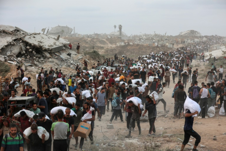 Des Palestiniens transportent des colis d'aides reçus à Beit Lahia dans le centre de la bande de Gaza, le 29 juillet 2025 ( AFP / Omar AL-QATTAA )