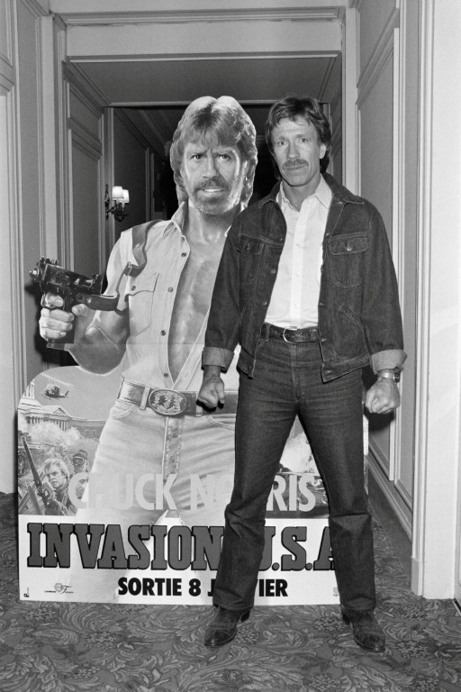 Chuck Norris pose devant l'affiche du film "Invasion USA", à Paris, le 27 novembre 1985 ( AFP / Pierre VERDY )