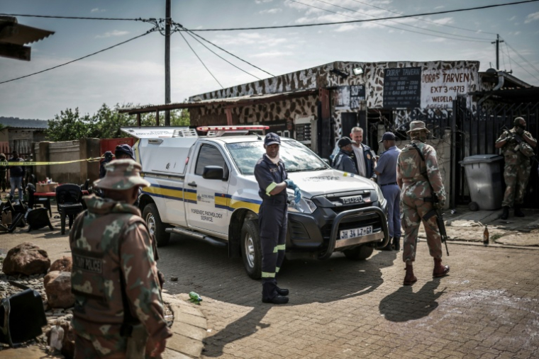 Des experts médicaux-légaux de la Force de défense nationale d'Afrique du Sud (SANDF) sur les lieux de la fusillade dans un bar de l'ouest de Johannesburg qui a fait 17 morts et 15 blessés, le 27 septembre 2026   ( AFP / EMMANUEL CROSET )