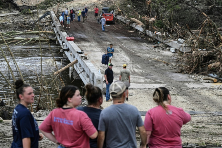 Des passants observant les forces de l'ordre et des bénévoles poursuivant leurs recherches pour retrouver les personnes disparues dans les inondations soudaines ayant frappées le centre du Texas, le 5 juillet 2025 ( AFP / RONALDO SCHEMIDT )