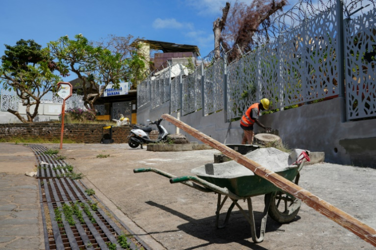 Un homme répare le mur d'une école de Mamoudzou, à Mayotte, le 18 août 2025 ( AFP / Marine GACHET )