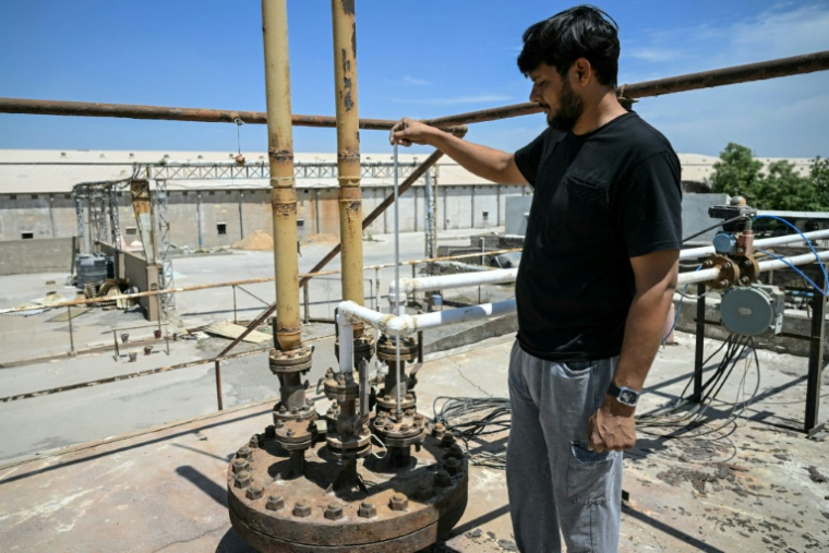 Un ouvrier mesure le niveau de gaz dans un réservoir de stockage presque vide d'une usine de fabrication de carreaux de céramique, fermée en raison des contraintes d'approvisionnement en propane, le 25 mars 2026 à Morbi, en Inde ( AFP / Indranil MUKHERJEE )