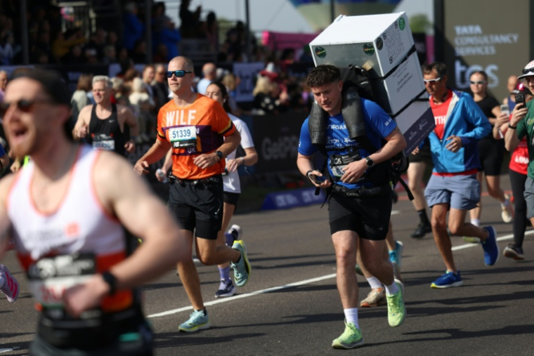 Le coureur Jordan Adams porte un frigo sur son dos au départ du marathon de Blackheath, à Londres, le 26 avril 2026 ( AFP / Toby Shepheard )