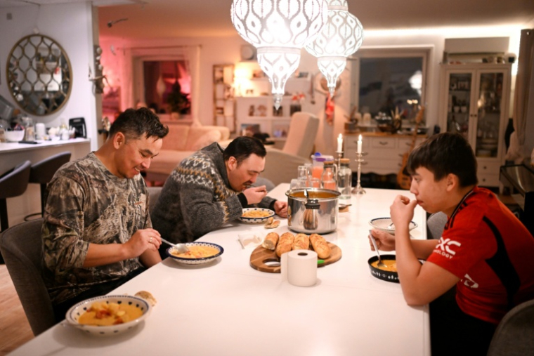 Le chasseur Malik Kleist (c), Karl Joregn et son fils mangent une soupe de poisson après une chasse infructueuse aux phoques, à Sisimiut, au Groenland, le 1er février 2026 ( AFP / Ina FASSBENDER )