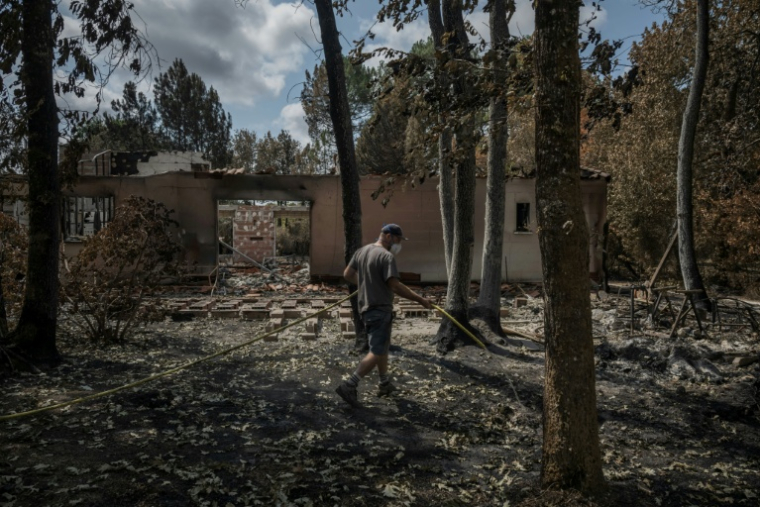 Un habitant éteint des brandons avec un tuyau d'arrosage dans la commune de Le Porge, en Gironde, ravagée par un incendie, le 31 juillet 2026  ( AFP / Ed JONES )