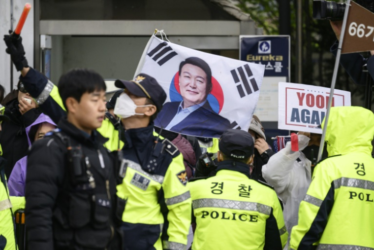 Des policiers attendent l'arrivée de l'ancien président sud-coréen Yoon Suk Yeol devant le tribunal deSéoul, le 14 avril 2025, face à des partisans de Yoon ( AFP / ANTHONY WALLACE )