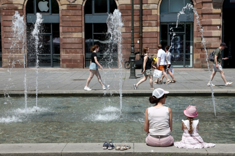 Des habitants et des touristes se rafraîchissent près de la fontaine de la place Kléber à Strasbourg, dans l'est de la France, le 19 juin 2025 ( AFP / FREDERICK FLORIN )