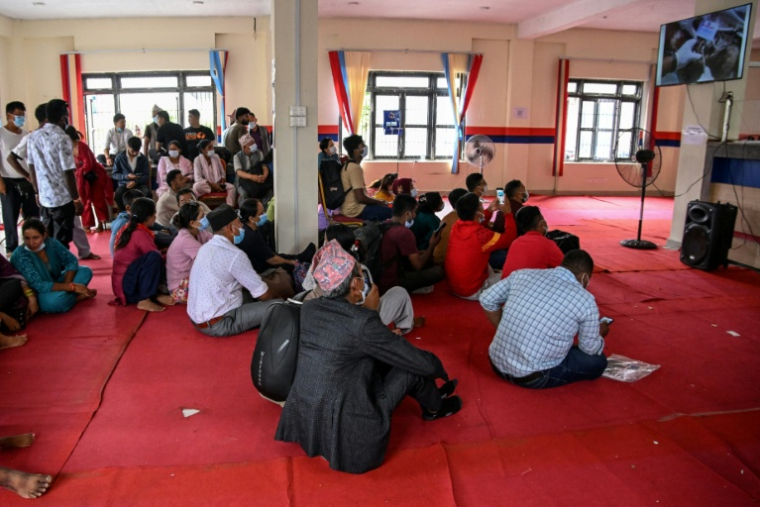 Des familles regardent un écran affichant les identités des victimes de la crue destructrice dans l'Himalaya, le 30 août 2026 Bharatpur, à l'ouest de Katmandou  ( AFP / Prakash MATHEMA )