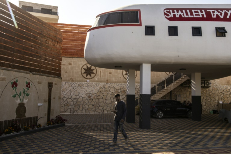Un homme passe dans un gîte touristique construit en forme d'avion à Qaffin, dans le nord de la Cisjordanie occupée, le 2 juillet 2025 ( AFP / John WESSELS )