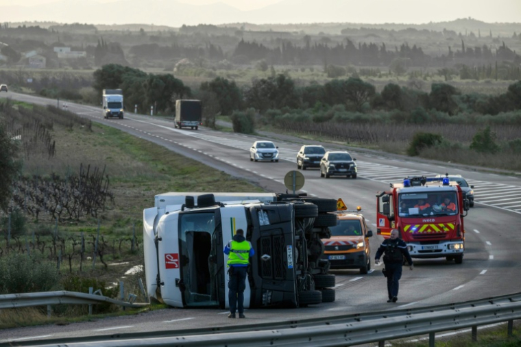 Un camion est couché sur le flanc sous l’effet de vents violents apportés par la tempête Nils près de Leucate (Aude), le 12 février 2026 ( AFP / Ed JONES )