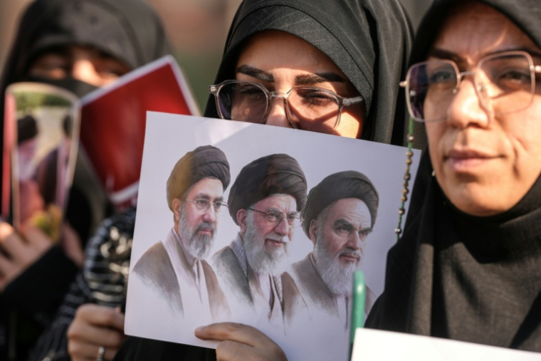 Des personnes en deuil tiennent une une photo du défunt fondateur de la République islamique, l'ayatollah Khomeini, du guide suprême défunt, l'ayatollah Khamenei, et de l'actuel guide suprême, Mojtaba Khamenei, lors du cortège funèbre de l'ayatollah Ali Khamenei à Nadjaf, le 8 juillet 2026 en Irak ( AFP / Qassem al-KAABI )