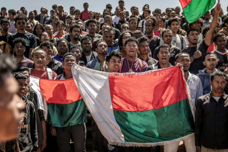 Des étudiants chantent l'hymne national en tenant des drapeaux malgaches avant de se rendre à un rassemblement de la société civile, à l'université Ankatso d'Antananarivo, le 13 octobre 2025 ( AFP / Luis TATO )