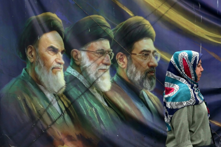 Une Iranienne passe devant les portraits des trois guides suprêmes iraniens depuis l'avènement de la République islamique, le 28 mai 2026 à Téhéran ( AFP / - )