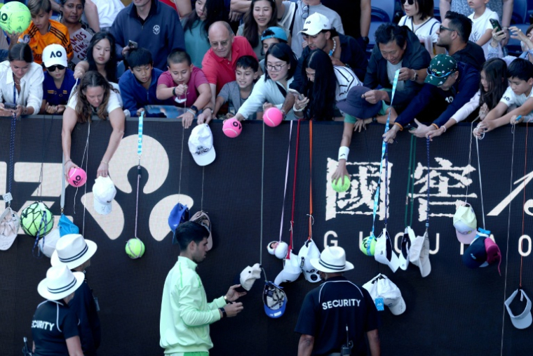 L'Espagnol Carlos Alcaraz (en bas) signe des autographes après avoir battu le Français Corentin Moutet au troisième tour de l'Open d'Australie, à Melbourne, le 23 janvier 2026 ( AFP / DAVID GRAY )