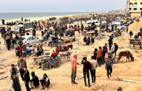 Des Palestiniens attendent l'arrivée de camions transportant des sacs de farine, près d'un point de contrôle israélien, dans la ville de Gaza