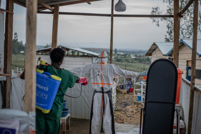 Un agent sanitaire décontamine un médecin quittant l'unité de soins aux patients du centre de traitement Ebola (CTE) de Rwampara, le 13 juillet 2026 à Bunia, dans la province de l'Ituri, en RDC ( AFP / BENEDICTION MURHABAZI )