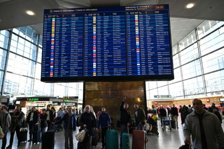 Des voyageurs consultent un panneau d'information sur les vols à l'aéroport de Copenhague, après un survol de drones, le 23 septembre 2025 au Danemark ( AFP / Sergei GAPON )