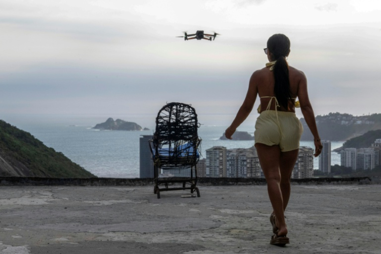 Une touriste se fait filmer par un drone sur le toit d'une maison dans la favela de Rocinha, à Rio de Janeiro, au Brésil, le 5 mars 2026 ( AFP / Pablo PORCIUNCULA )